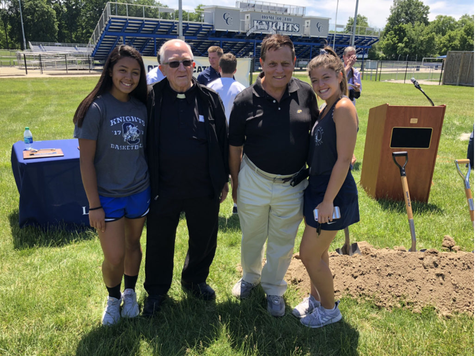 Fr. Fox and Chuck Sanchelli with 2018 seniors and tennis players, Sami Royer and Lizzie Cramer, at Tennis Court Groundbreaking